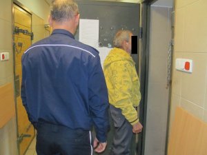 Policjant z zatrzymanym mężczyzną przed drzwiami celi