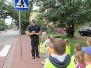 Policjant z przedszkolakami na chodniku