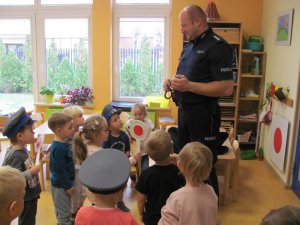 Policjant zapoznaje dzieci w przedszkolu z wyposażeniem służbowym