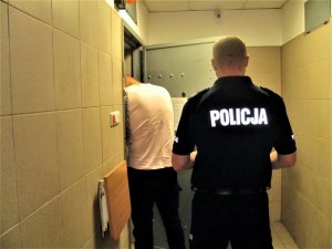 Policjant z zatrzymanym mężczyzną przed celą