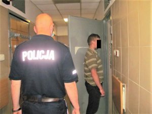 Policjant z jednym z zatrzymanych mężczyzn przed celą