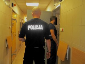 Policjant z zatrzymanym mężczyzną przed celą