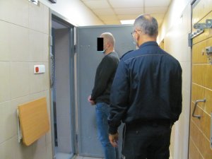 Policjant z zatrzymanym mężczyzną przed celą