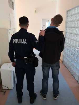 Policjant z zatrzymanym mężczyzną w budynku komisariatu