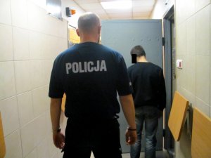 Policjant z zatrzymanym mężczyzną przed celą