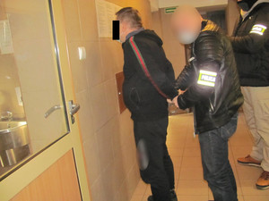 Policjanci z zatrzymanym mężczyzną w pomieszczeniu dla zatrzymanych