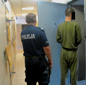 Policjant z zatrzymanym mężczyzną przed celą