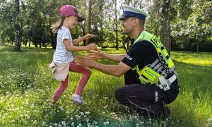 Policjant z dzieckiem na łące