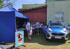 Policjant podczas pikniku przy stanowisku- namiot policyjny i radiowóz