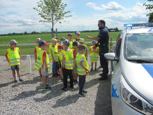 Policjant przy radiowozie rozmawia z grupą dzieci