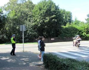 Policjantka, osoby piesze i motocykl na jezdni