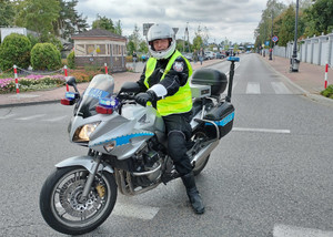 Policjant ruchu drogowego na motocyklu pilotuje kolarzy