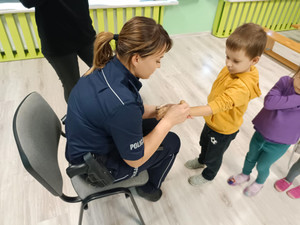 Policjantka na spotkaniu z przedszkolakami- wykonuje pamiątkowy stempel na ręce dziecka