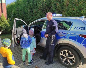 Policjant z dziećmi przy radiowozie