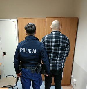 Policjant z jednym z zatrzymanych mężczyzn w pokoju służbowym