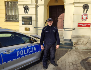 Policjant przy radiowozie przed budynkiem Komendy Stołecznej Policji