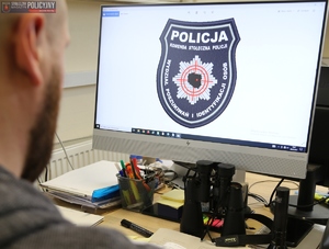 emblemat wydziału na ekranie komputera i sylwetka policjanta przed nim
