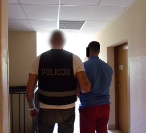Policjant i zatrzymany mężczyzna na korytarzu komendy