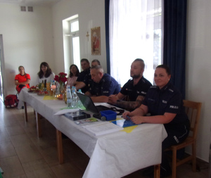 Uczestnicy debaty- policjanci i inne osoby siedzą przy stole