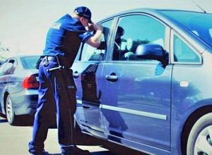 policjant przy samochodzie patrzy przez szybę