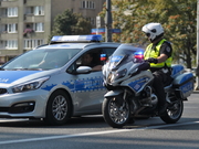 Radiowóz i policjant na motocyklu , a w tle osiedle i droga