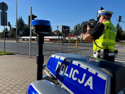 policjant drogówki z miernikiem prędkości podczas działań na drodze, obok motocykl