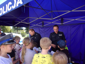 Policjanci przy stanowisku na pikniku z grupą dzieci