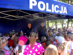 Policjanci przy stanowisku na pikniku z grupą dzieci wokół