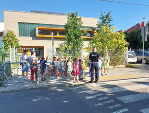Policjant z grupą dzieci przed przejściem dla pieszych