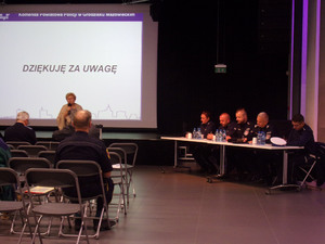 Policjanci za stołem i uczestnicy debat w sali