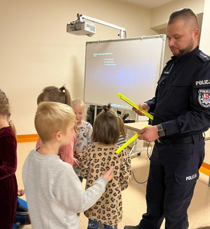 Policjant wręcza dziecku opaskę odblaskową