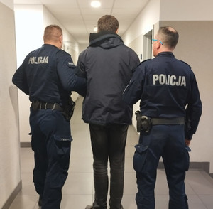 Dwóch policjantów prowadzi zatrzymanego korytarzem komisariatu