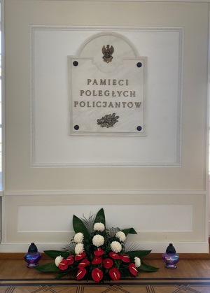 Tablica z napisem Pamięci Poległych Policjantów i kwiaty, znicze pod nią