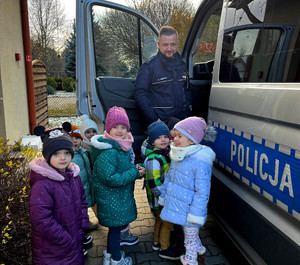 Policjant przy radiowozie z dziećmi