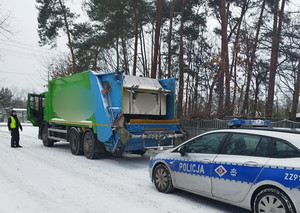 Policjant rozmawia z kierowca pojazdu specjalnego, za nim radiowóz