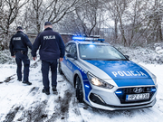 dwóch umundurowanych policjantów przy radiowozie w zimowych warunkach