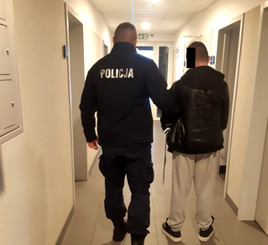 Policjant prowadzi korytarzem jednostki zatrzymanego