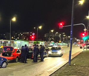 Grupa policjantów i radiowozy w miejscu zatrzymania podejrzanego auta