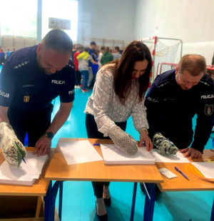Policjanci i nauczyciel podczas konkurencji pisania w rękawicy
