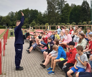 Policjant prowadzi zajęcia na boisku szkolnym z grupą uczniów