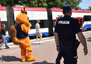 Policjanci i maskotka na peronie, w tle pociąg WKD