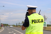 Policjant w kamizelce z urządzeniem mierzącym prędkość podczas służby na drodze