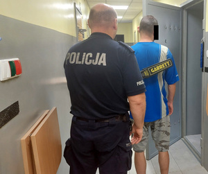 Policjant z zatrzymanym mężczyzną przed celą