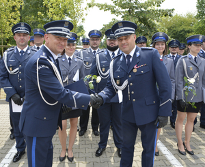 Grupa policjantów w tle, komendanci podczas gratulacji