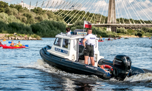 policjant na łodzi służbowej na wodzie i osoby wokół