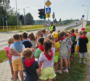 policjant z grupą dzieci przed przejściem dla pieszych