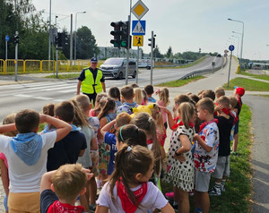 Policjant z grupą dzieci przed przejściem dla pieszych