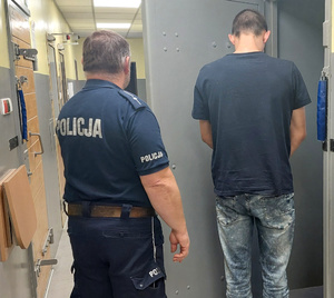 Policjant z zatrzymanym mężczyzną przed celą