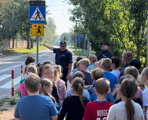 Policjanci z grupą uczniów przed przejściem dla pieszych