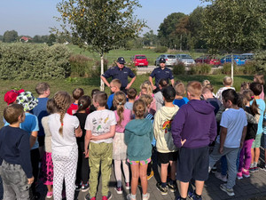 Policjanci z grupa uczniów na dziedzińcu szkoły